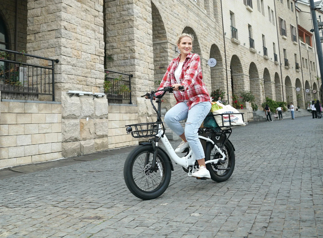 Woman riding the DYU C9 folding e-bike on a cobblestone shopping street
